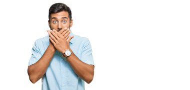 Sıradan kıyafetler giyen yakışıklı İspanyol adam yanlışlıkla elleri ile ağzını kapatırken şok oldu. gizli kavram. 