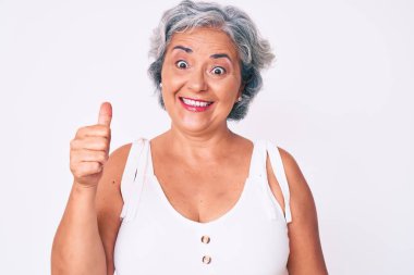 Kıdemli İspanyol kadın günlük kıyafetler giyiyor mutlu ve pozitif gülümsüyor, başparmağı mükemmel ve onay işareti yapıyor. 