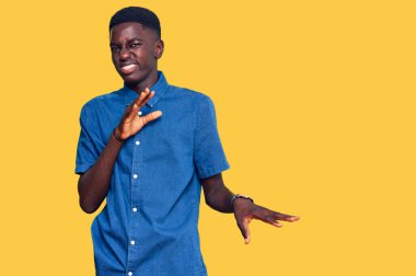 Genç Afro-Amerikan adam günlük giysiler giyiyor, tiksindirici ifadeler takınıyor, tiksindirici ifadeler takınıyor, tiksindirici ifadeler takınıyor.. 