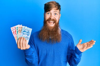 Genç İrlandalı kızıl adam Yuan Çin banknotlarını tutarak başarıyı mutlu bir gülümsemeyle ve kazanan ifadeyle kutluyor. 