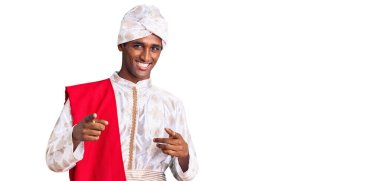 Gelenek giyinmiş Afrikalı yakışıklı bir adam Sherwani sari elbiseleri giyiyor ve mutlu ve komik yüzüyle kamerayı işaret ediyor. iyi enerji ve titreşimler. 