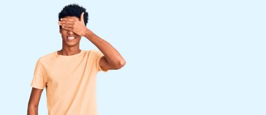 Sıradan kıyafetler giyen, gülümseyen ve gülen genç Afro-Amerikan erkeği şaşırtmak için gözlerini kapatıyor. kör kavram. 