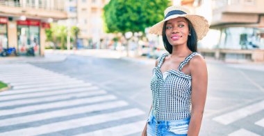 Genç Afro-Amerikan kadın tatilde gülümsüyor ve şehrin sokaklarında mutlu bir şekilde yürüyor.