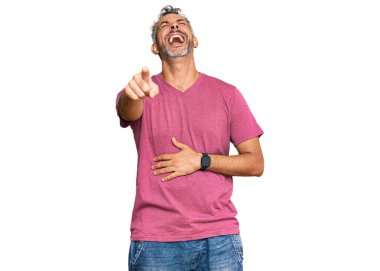 Orta yaşlı, gri saçlı, sıradan kıyafetler giyen, sana gülen, eli vücudunun üzerinde kamerayı gösteren, utanç ifadesi olan bir adam. 