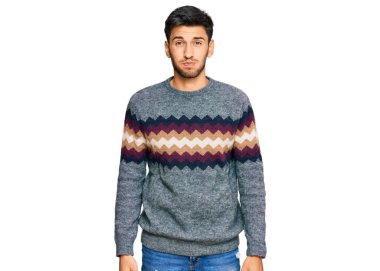 Kış süveteri giyen genç yakışıklı adam komik yüzlü yanakları şişiriyor. Havayla şişmiş ağız, çılgın bir ifade.. 