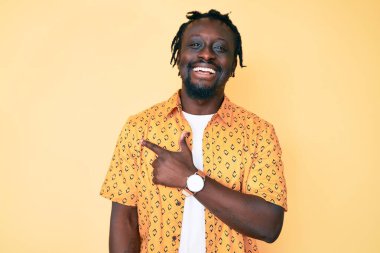 Saçları örgülü, neşeli, yüzü gülücüklü, elleri ve parmaklarıyla yüzünü gösteren mutlu ve doğal bir ifadeyle Afro-Amerikalı genç bir adam. 