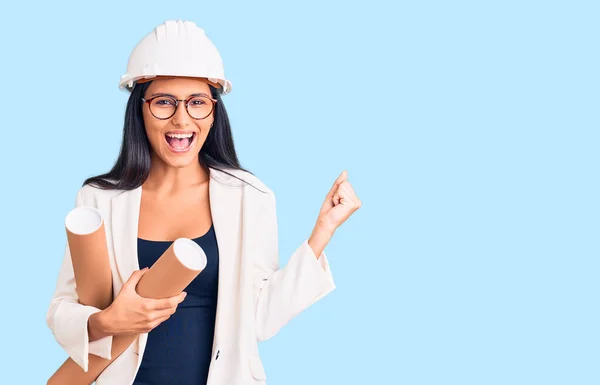 Joven Chica Latina Hermosa Usando Hardhat Arquitecto Sosteniendo Planos Gritando —  Fotos de Stock