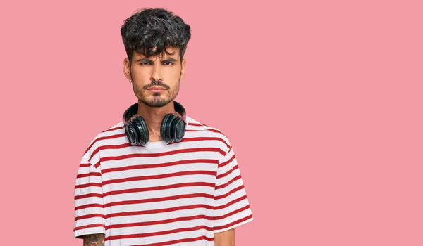 Hombre Hispano Joven Escuchando Música Usando Auriculares Escépticos Nerviosos Frunciendo —  Fotos de Stock