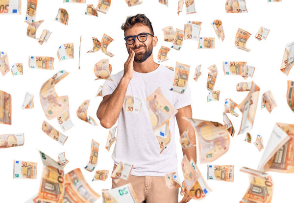 Молодой латиноамериканец в повседневной одежде и очках касается рта рукой с болезненным выражением лица из-за зубной боли или зубной болезни на зубах. стоматолог