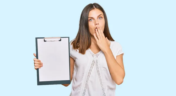 Young Caucasian Woman Holding Clipboard Blank Space Covering Mouth Hand — Stock Photo, Image