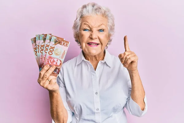 Старшая Седовласая Женщина Банкнотой 100 Новых Зеландских Долларов Улыбается Идеей — стоковое фото