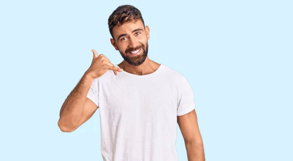 Latin Asıllı Genç Adam Günlük Beyaz Tişört Giyip Gülümsüyor Telefonla — Stok fotoğraf