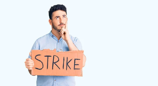 Young Hispanic Man Holding Strike Banner Cardboard Serious Face Thinking — Stock Photo, Image