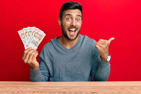 Hombre Hispano Guapo Sosteniendo Billetes Chinos Yuan Señalando Pulgar Hacia — Foto de Stock