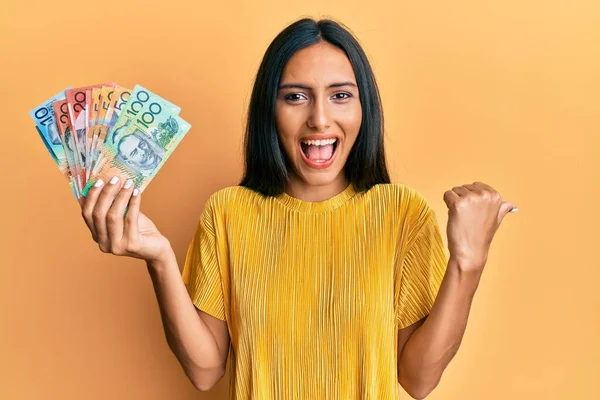 Avustralya Doları Tutan Genç Esmer Kadın Başparmağıyla Yan Tarafı Işaret — Stok fotoğraf