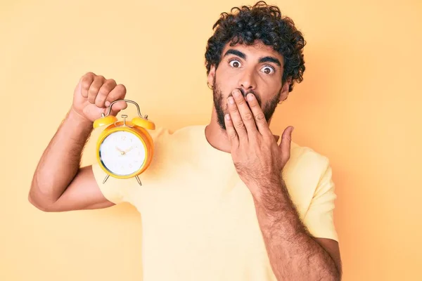 Jovem Bonito Com Cabelo Encaracolado Urso Segurando Despertador Cobrindo Boca — Fotografia de Stock