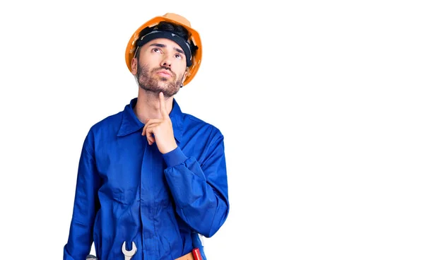 Young Hispanic Man Wearing Worker Uniform Thinking Concentrated Doubt Finger Stock Photo