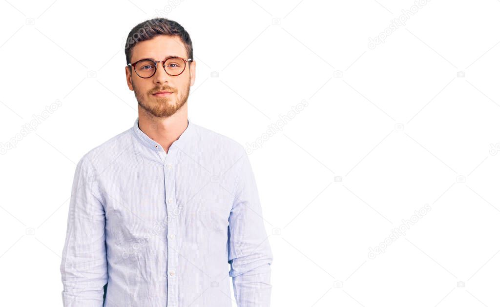 Handsome young man with bear wearing elegant business shirt and glasses relaxed with serious expression on face. simple and natural looking at the camera. 