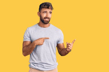 Gündelik kıyafetler giyen genç İspanyol bir adam iki eliyle endişeli ve endişeli bir ifadeye işaret ediyor. 