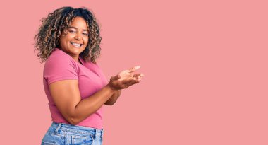 Genç Afro-Amerikan artı cüsseli kadın, sıradan kıyafetler giyip avuç içlerini açıp fotokopi alanını gösteren, gülümseyerek mutlu bir gülümseme sunuyor. 