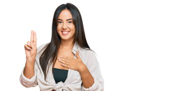 Genç, güzel İspanyol bir kız, günlük kıyafetler giymiş, gülümsüyor, el ve göğsü havada küfür ediyor, sadakat yemini ediyor. 