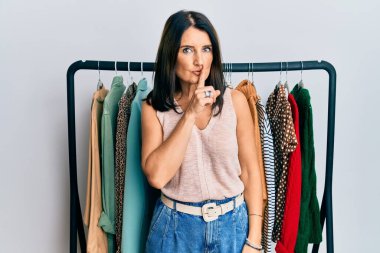 Profesyonel alışverişçi olarak çalışan orta yaşlı esmer kadın dudakları dudaklarında sessiz olmak istiyor. sessizlik ve gizli konsept. 