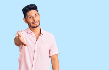 Yakışıklı Latin Amerikalı rahat bir yaz gömleği giyen neşeli gülümseyerek avuç içi yardım eli uzatan ve kabul gören genç adam.. 