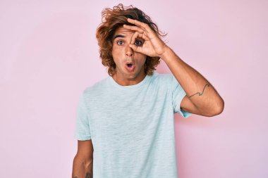 Gündelik kıyafetler giyen genç İspanyol adam şaşırmış yüz ifadesiyle şok olmuş, parmaklarından bakan gözler. İnançsız ifade. 