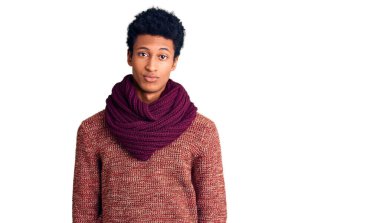 Genç Afro-Amerikan adam günlük kışlık süveter ve atkı giyiyor. Uykulu ve yorgun görünüyor. Yorgun ve akşamdan kalma, tembel gözleri var.. 