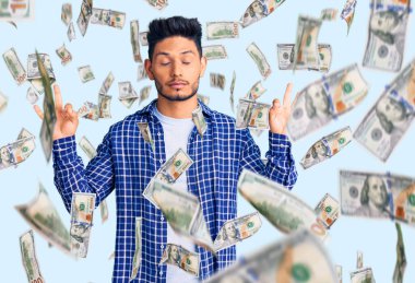 Yakışıklı Latin Amerikalı rahat gömlekler giyen rahat ve gözleri kapalı gülümseyen parmaklarıyla meditasyon hareketi yapan genç adam. yoga konsepti.