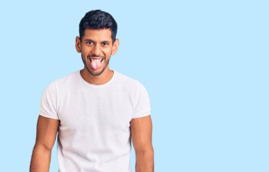 Gündelik kıyafetler giyen genç latin adam komik bir ifadeyle dilini dışarı çıkartıyor. duygu kavramı. 