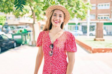 Genç sarışın kadın tatilde gülümsüyor. Mutlu bir şekilde caddede yürüyor.