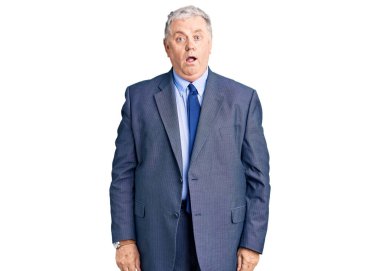 Şok suratlı, iş ceketi giyen yaşlı gri saçlı adam şüpheci ve alaycı görünüyor, ağzı açık kalınca şaşırıyor. 