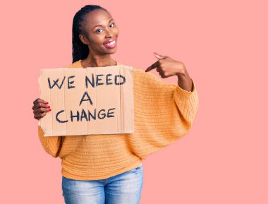 Genç Afrikalı Amerikalı kadın elinde bir değişim pankartı tutarken mutlu bir gülümsemeye ihtiyacımız var. 