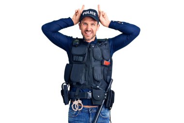 Polis üniforması giyen genç yakışıklı komik ve çılgın poz veren parmakları tavşan kulaklı, neşeli gülümseyen 