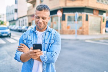 Beyaz adam şehirde akıllı telefon kullanarak mutlu bir şekilde gülümsüyor..