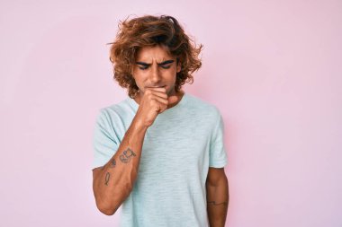 Günlük kıyafetler giyen genç İspanyol adam kendini iyi hissetmiyor ve soğuk algınlığı veya bronşitin belirtisi olarak öksürüyor. sağlık hizmeti kavramı. 