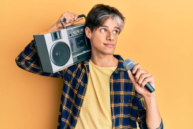 Genç İspanyol adam mikrofon ve teyp kullanarak şarkı söylüyor. Gülümsüyor, yan tarafa bakıyor ve düşünüyor.. 