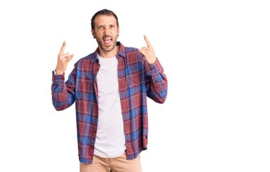 Genç, yakışıklı, günlük kıyafetler giymiş, çılgın bir ifadeyle bağıran, elleri havada rock sembolü yapan bir adam. Müzik yıldızı. ağır müzik konsepti. 