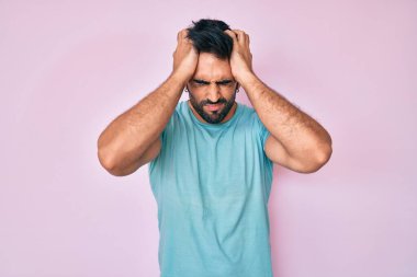 Yakışıklı, sakallı, günlük kıyafetler giyen, baş ağrısı çeken, çaresiz ve stresli bir adam. Çünkü acı ve migren ağrısı var. Eller başının üstünde.. 