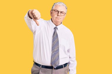 Yaşlı, gri saçlı, iş kıyafetleri giymiş mutsuz, kızgın, reddedilmiş ve olumsuz davranışlar sergileyen bir adam. kötü ifade. 