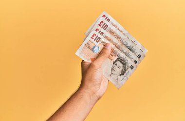 İspanyol bir adamın elinde 5 kilo banknotla izole edilmiş sarı arka plan..