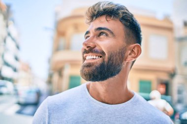 Genç İspanyol adam gülümseyerek şehirde mutlu bir şekilde yürüyor.