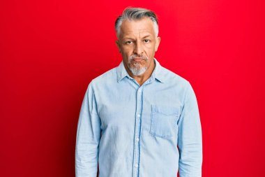 Orta yaşlı, gri saçlı, günlük giysiler giyen sıkıntılı ve endişeli, sinirli ve korkmuş bir adam. hüzünlü ifade. 