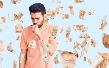 Sakallı, sıradan bir tişört giyen, kendini kötü hisseden ve soğuk algınlığı veya bronşitin belirtisi olarak öksüren genç yakışıklı bir adam. sağlık hizmeti kavramı.