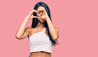 Güzel İspanyol kadın gündelik kıyafetler giyip kalp şeklinde elleriyle ve parmaklarıyla tabelanın içinden bakıp gülümsüyor. 