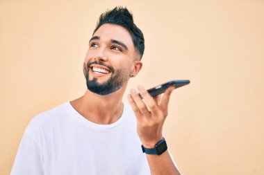 Genç Arap adam gülümsüyor. Şehirdeki akıllı telefonu kullanarak sesli mesaj gönderiyor..