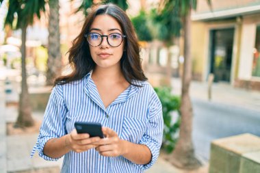 Şehirde akıllı telefon kullanan ciddi bir suratı olan genç İspanyol iş kadını..
