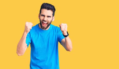 Genç, sakallı, rahat tişörtlü, sinirli, kızgın ve öfkeli bir adam öfkeyle bağırırken sinirli yumruklar sallıyor. öfke ve agresif konsept. 