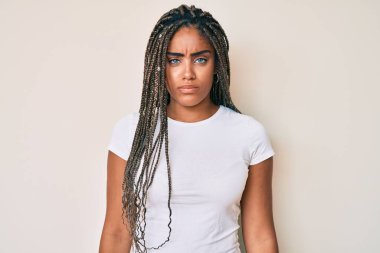 Young african american woman with braids wearing casual white tshirt skeptic and nervous, frowning upset because of problem. negative person. 